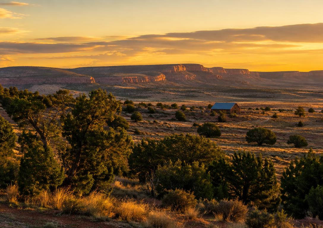 Golden hour over an Arizona high desert mesa with a distant ranch barn